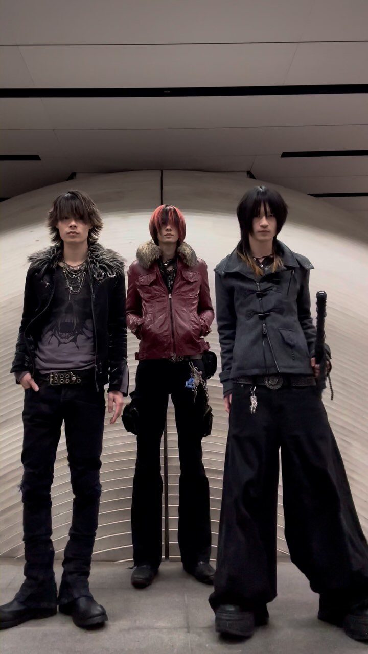 Three people posing in dark, edgy Japanese street fashion with heavy boots and layered clothing.