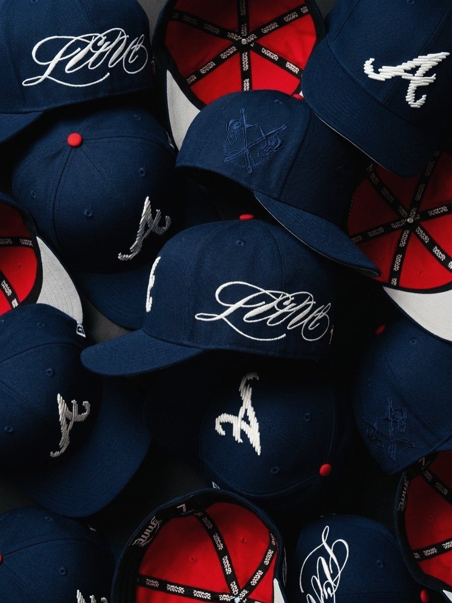 Multiple navy blue baseball caps with white embroidery arranged in a pile.