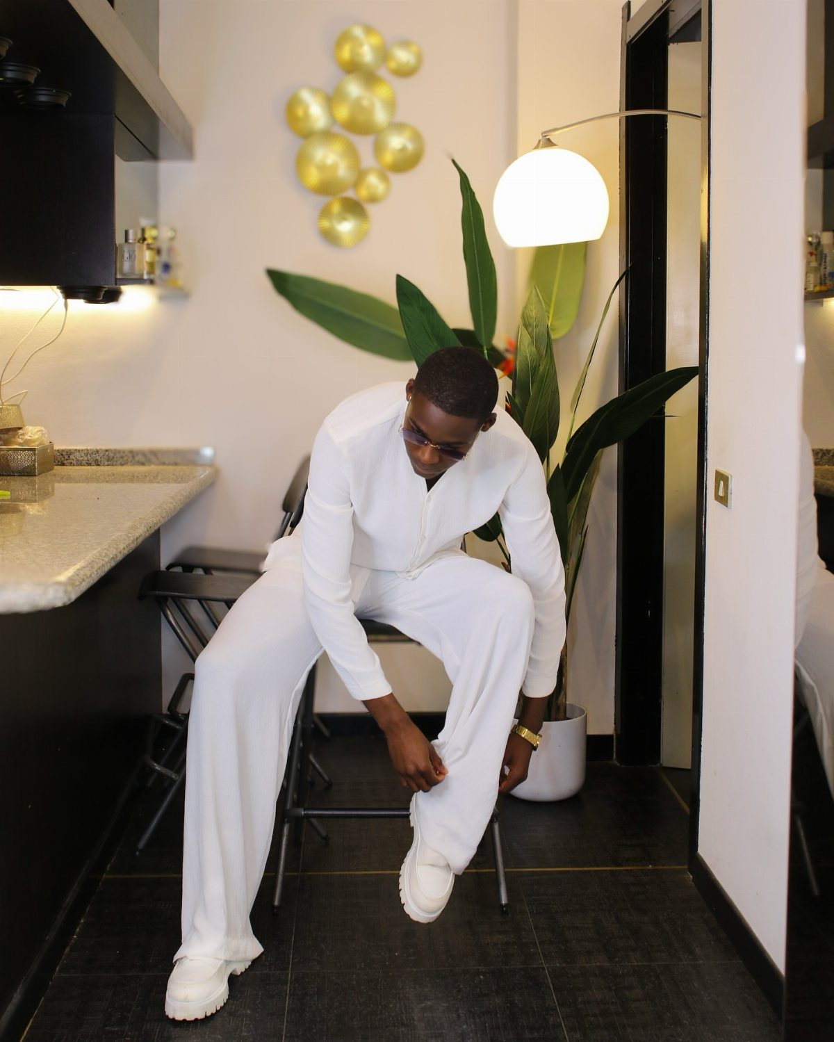 A man dressed in an all-white ensemble including a shirt, trousers, and sneakers.