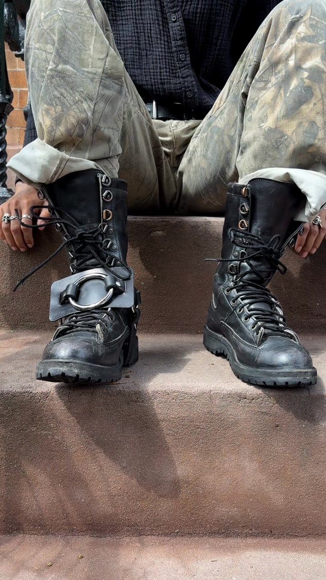 Black chunky combat boots worn with baggy patterned pants on concrete steps.