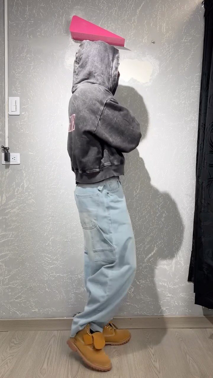 Person wearing a dark grey hoodie, light blue baggy jeans, and tan boots.