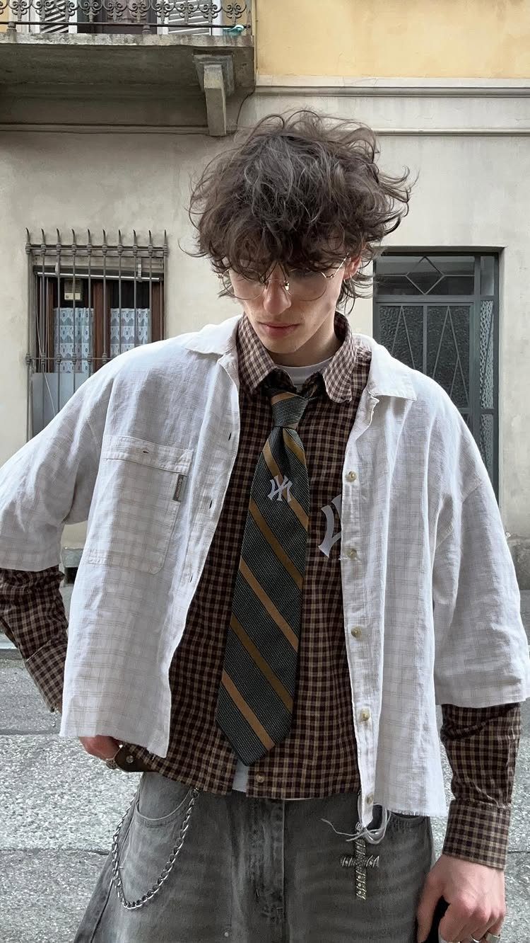 A person wearing a brown checkered shirt layered under a white short-sleeved shirt with a tie.