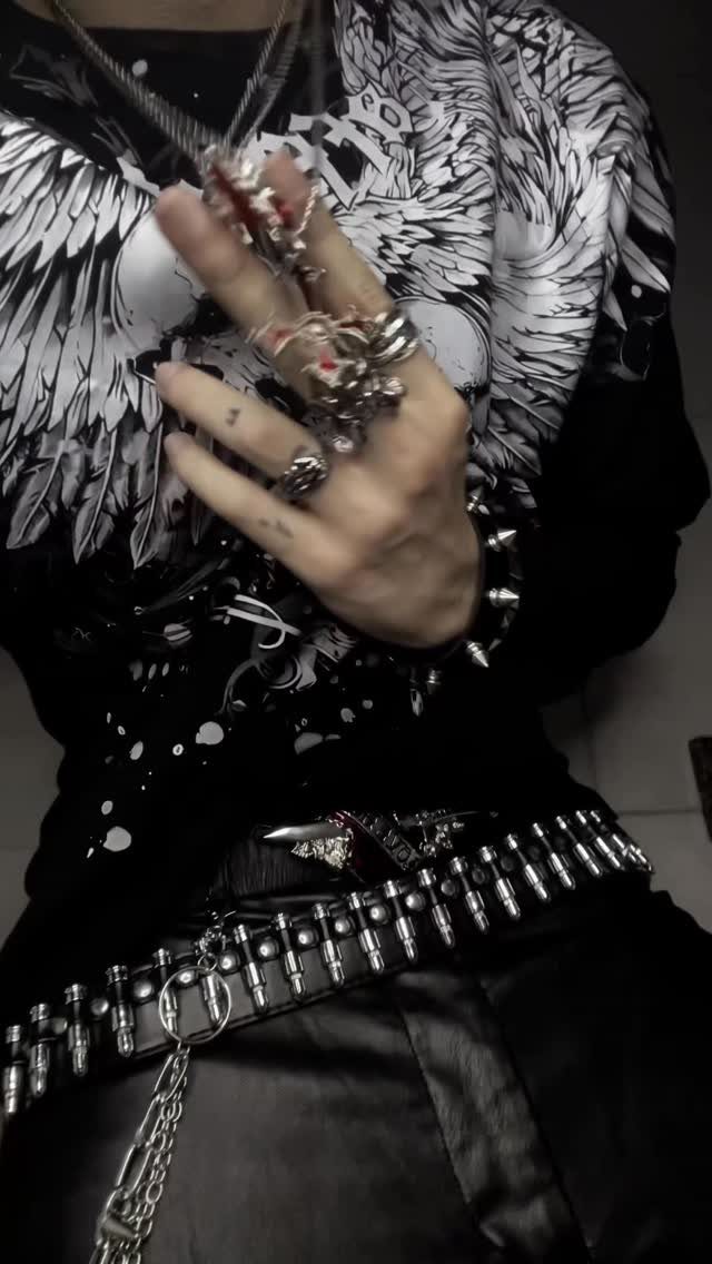 A person wearing a black graphic tee and a black leather belt with silver metal studs.