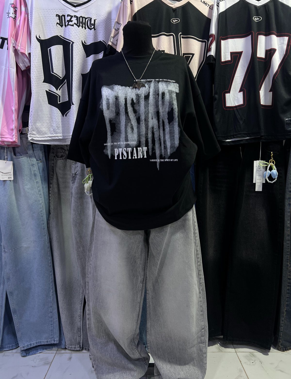 Black graphic t-shirt and grey baggy jeans displayed on a mannequin.