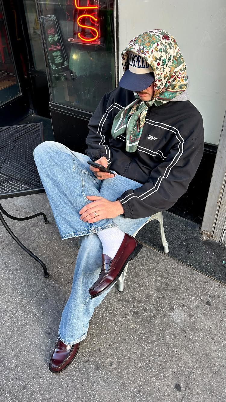 Person sitting in a chair wearing light blue baggy jeans and burgundy leather loafers.