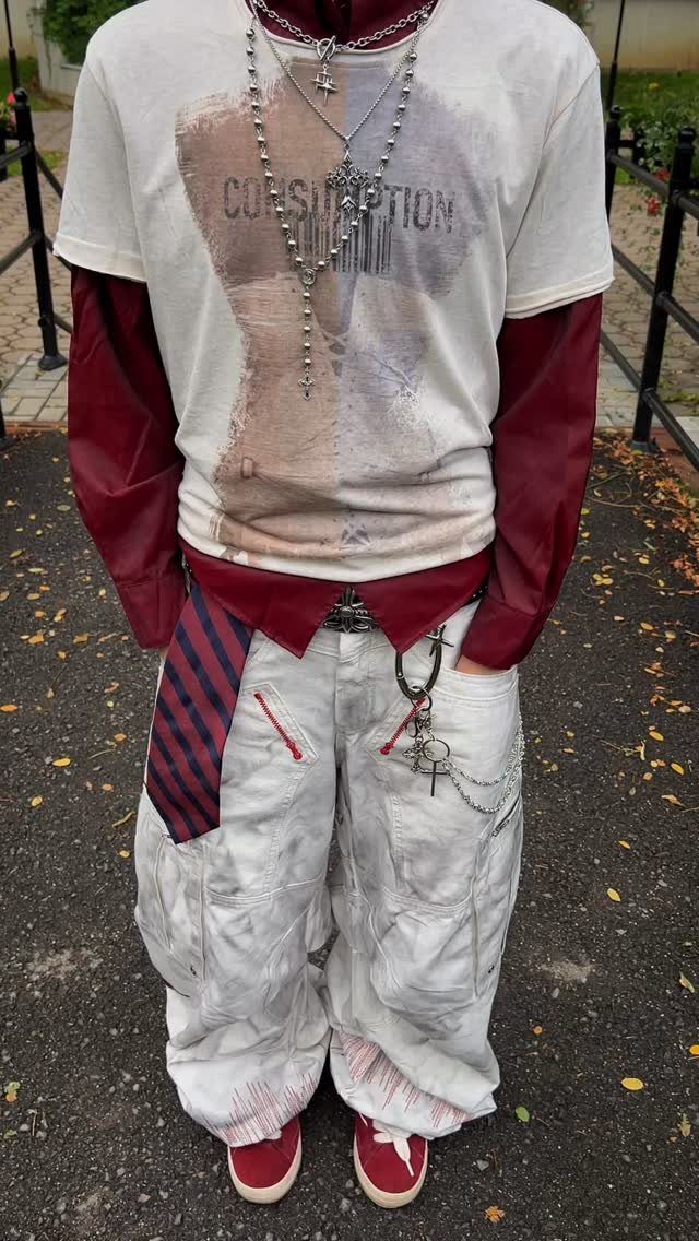 Person wearing a white graphic t-shirt over a burgundy long-sleeve shirt and baggy cargo pants.
