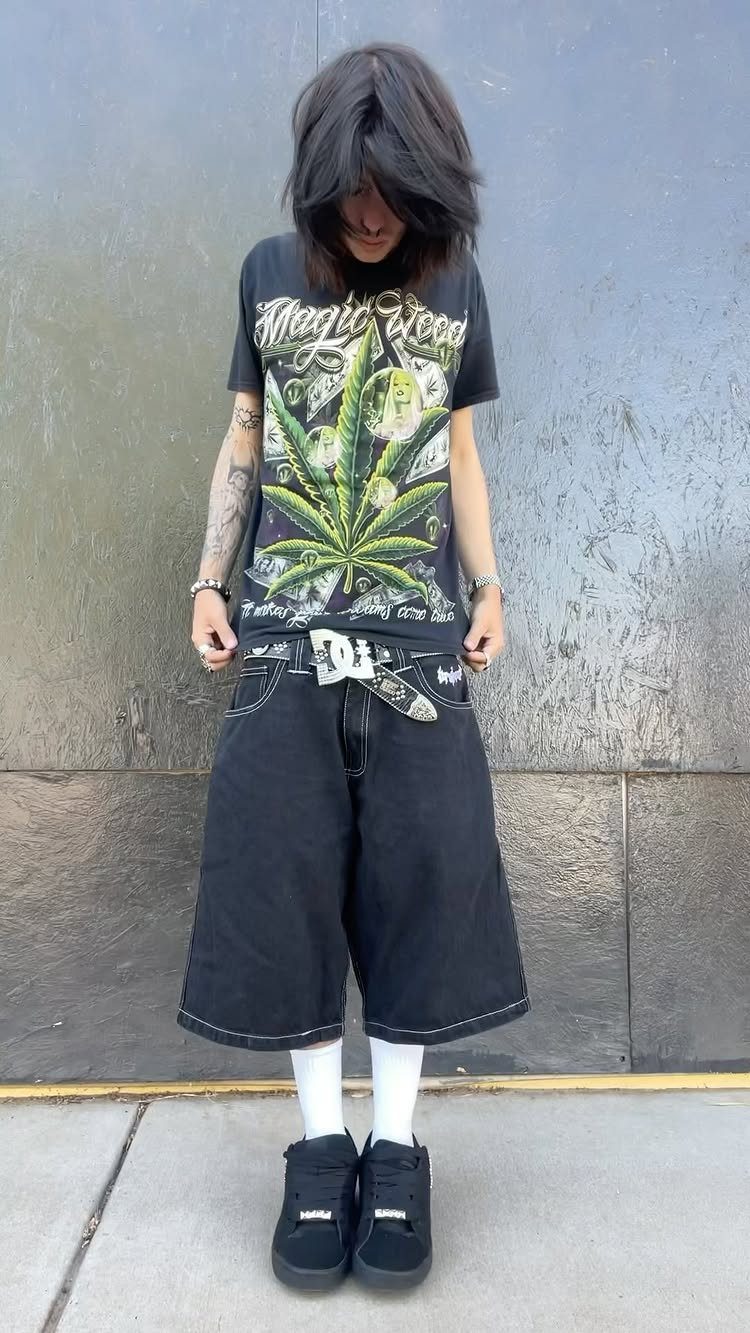 Person wearing a black graphic t-shirt and wide black denim shorts with white stitching.