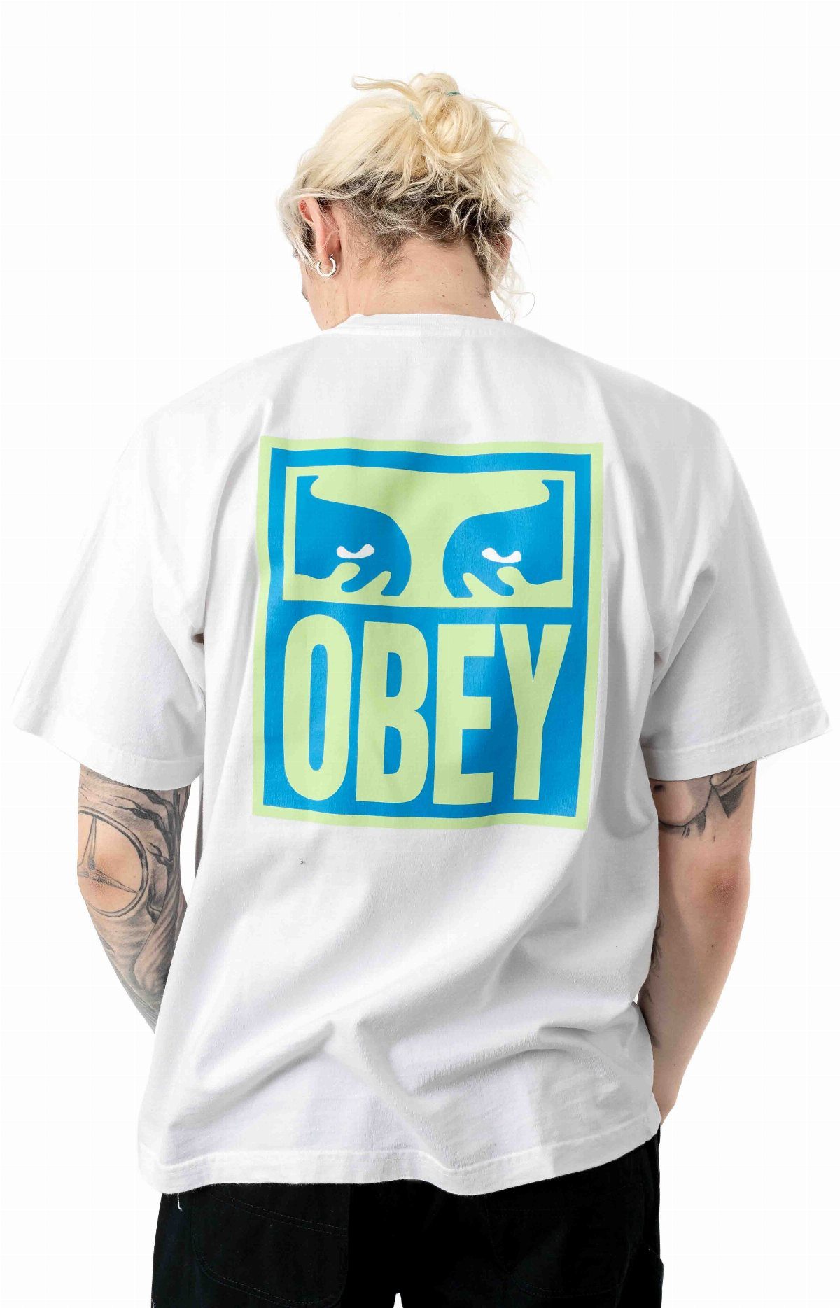 Person wearing a white t-shirt with a large blue and green Obey graphic on the back.