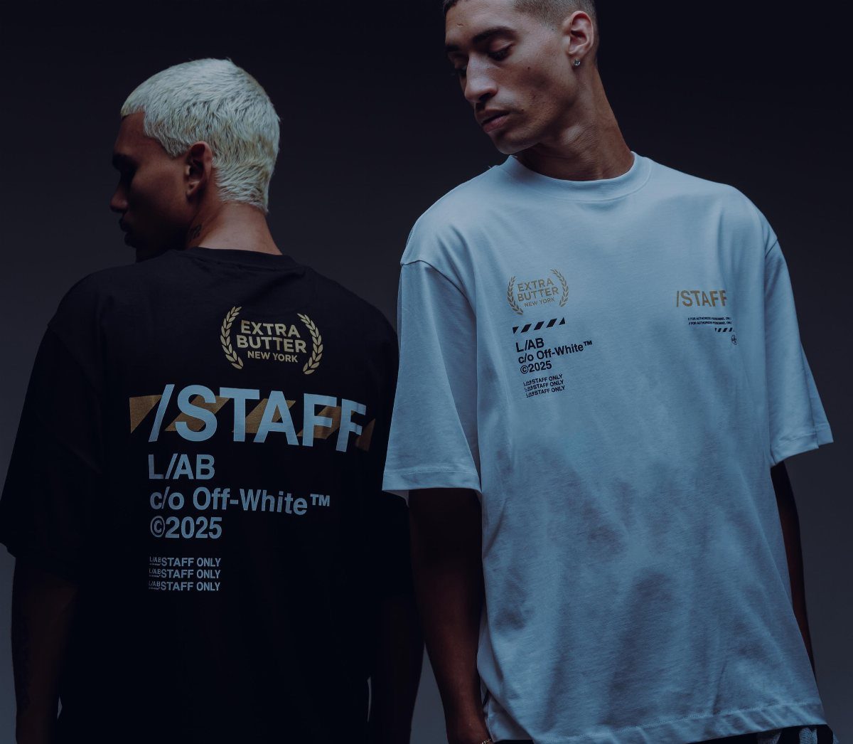 Two men wearing graphic streetwear t-shirts with Off-White branding in a dark studio.