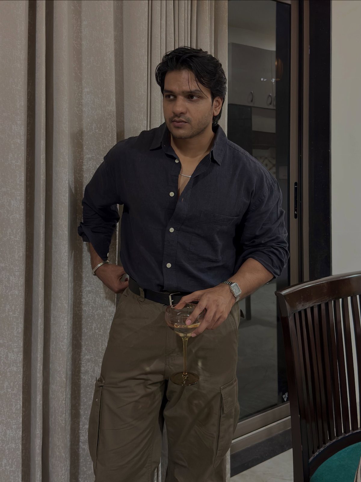 Man wearing a dark navy button-down shirt and tan cargo pants standing indoors.