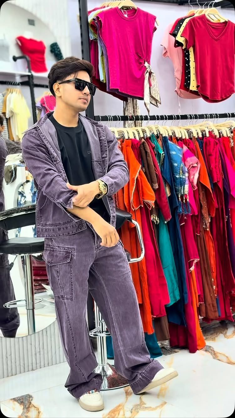 A man in a purple jacket and matching cargo pants posing in a clothing store.