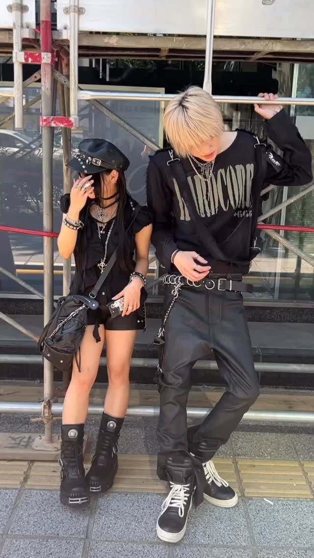 Two people posing in black grunge outfits with leather pants, combat boots, and silver accessories.
