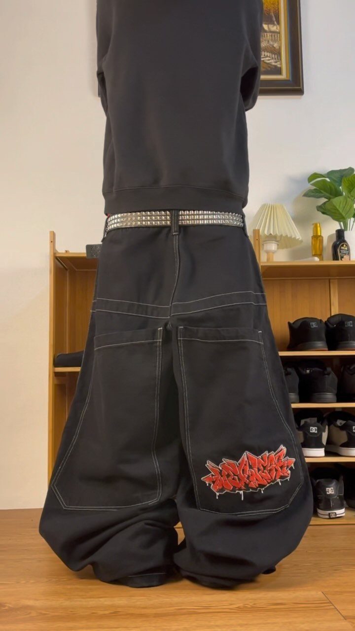 Person wearing an oversized black sweatshirt and very baggy black cargo pants with white stitching.