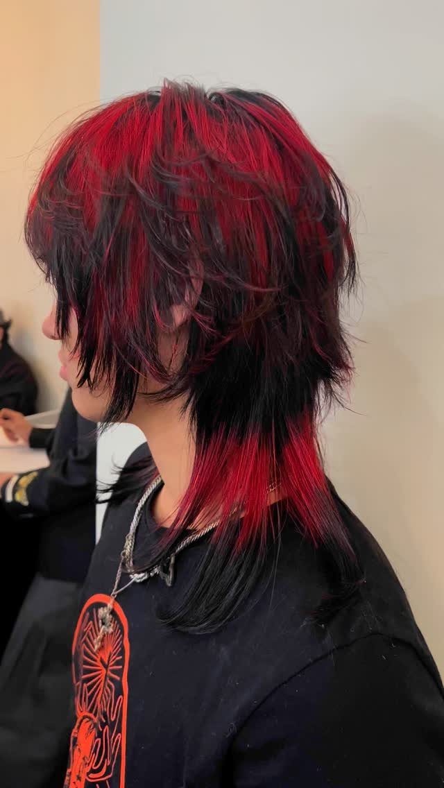 A person with choppy, layered hair dyed in vibrant red and black colors.