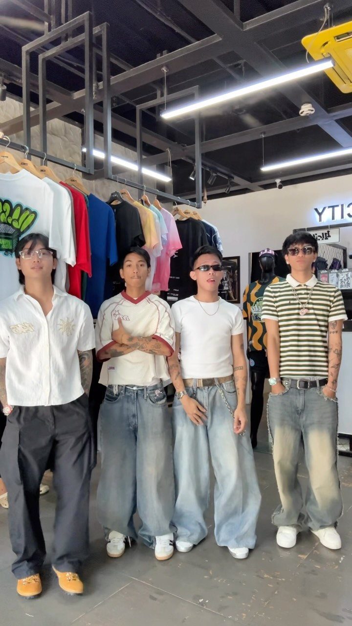 Four young men posing in a clothing store wearing various styles of baggy streetwear and denim.