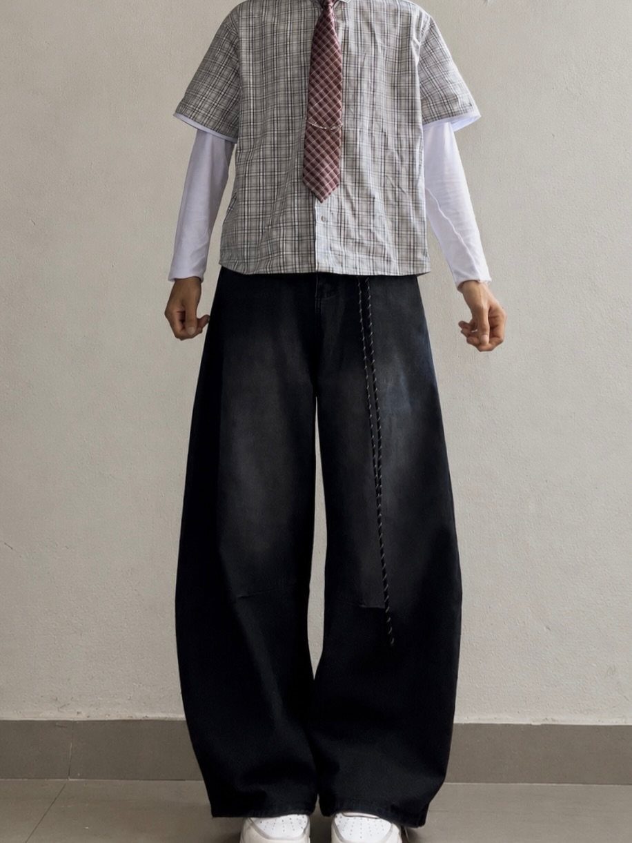 Person wearing oversized black baggy pants with a patterned shirt and red tie.