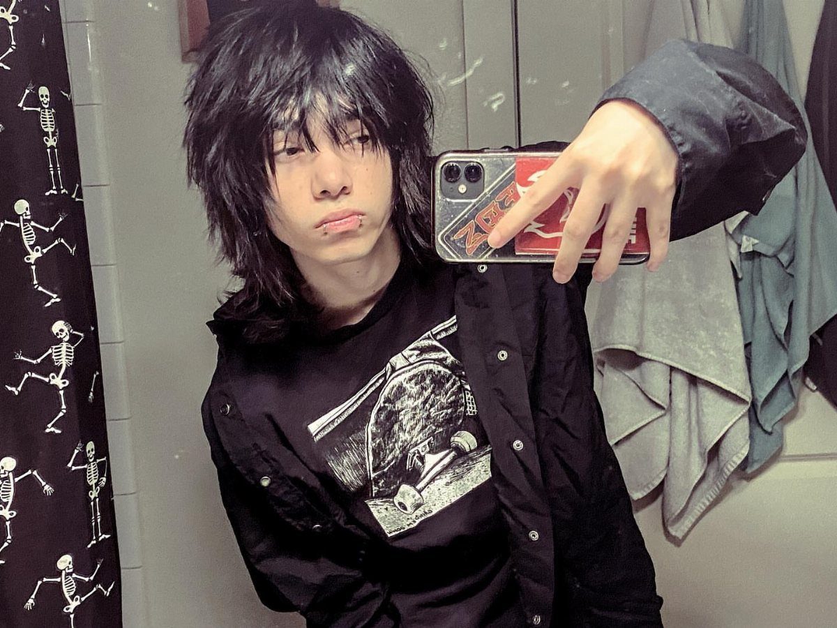 Person with messy black hair wearing a black graphic t-shirt and taking a selfie.