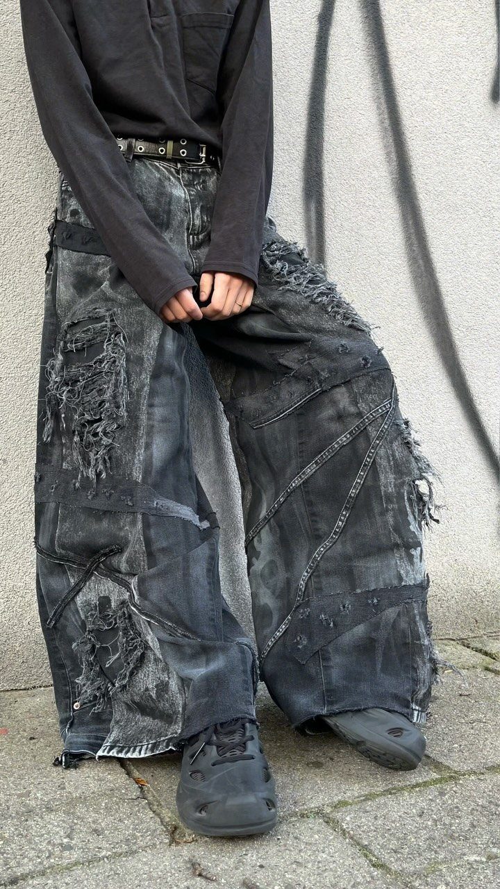 Person wearing oversized, heavily ripped and distressed wide-leg black denim pants.