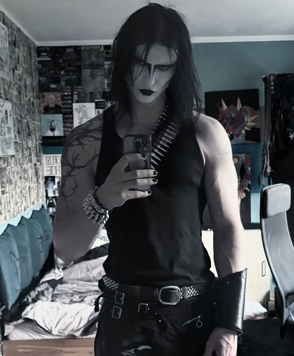 Man with long black hair and heavy gothic makeup posing in a black tank top.