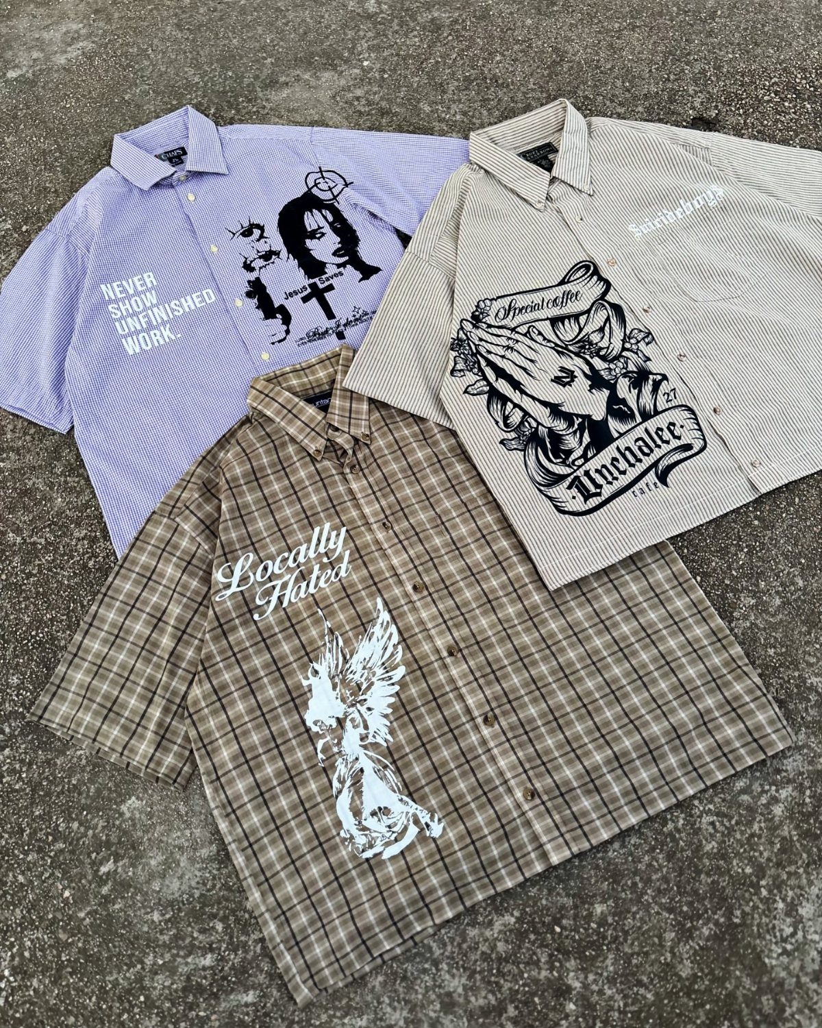 Four patterned button-down shirts with large graphic prints laid flat on a grey ground.