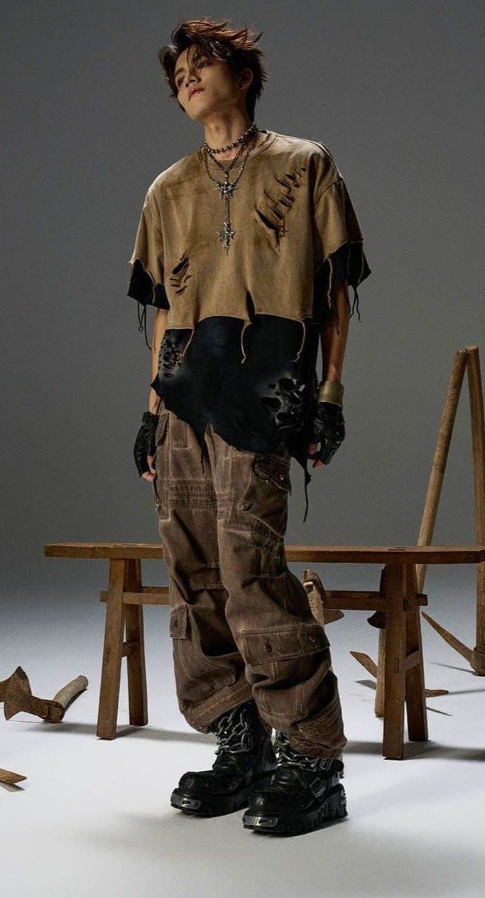 A person posing in distressed tan clothing, cargo pants, and chunky black boots.
