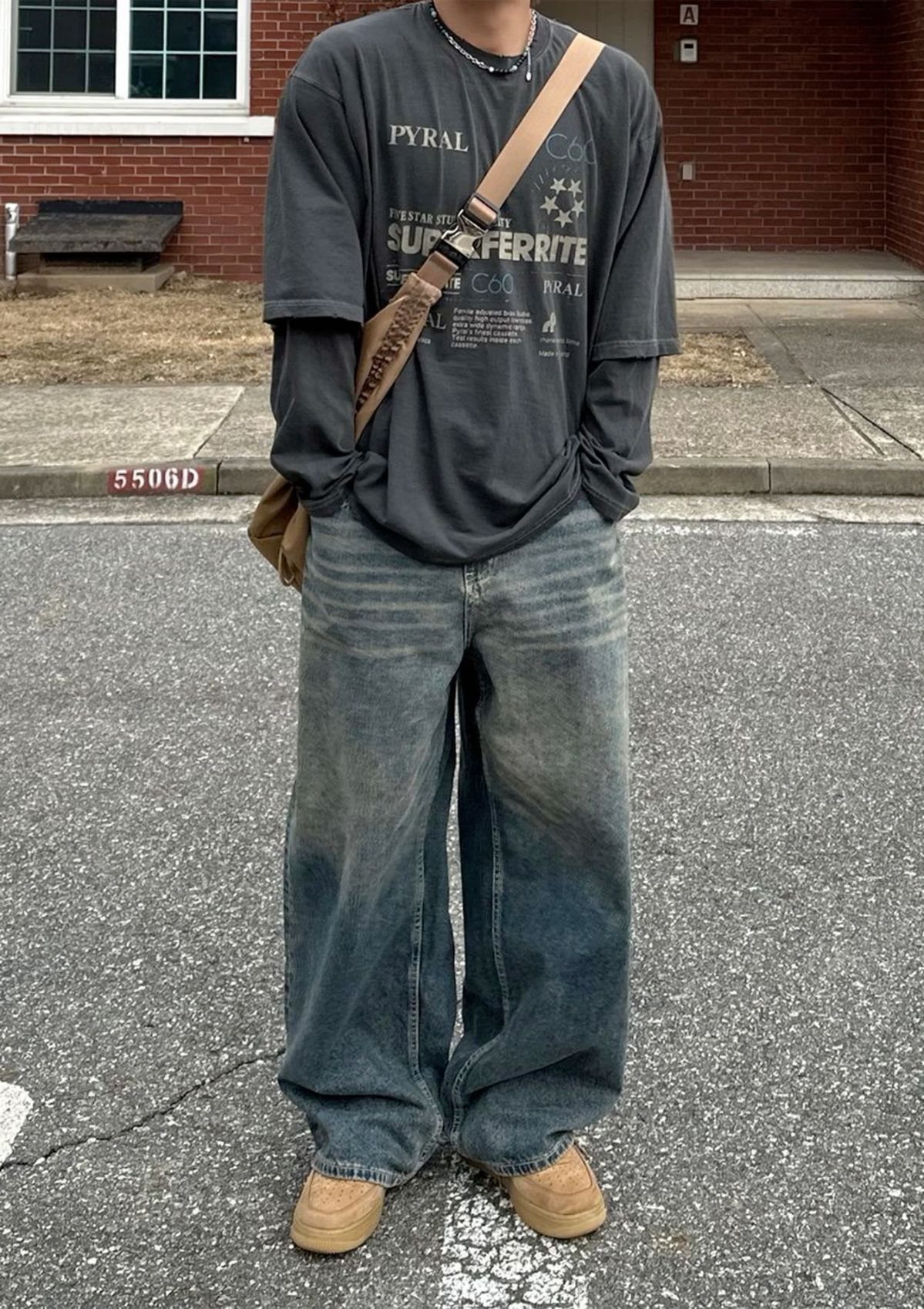 Person wearing a faded dark grey graphic t-shirt and wide-leg blue denim jeans.