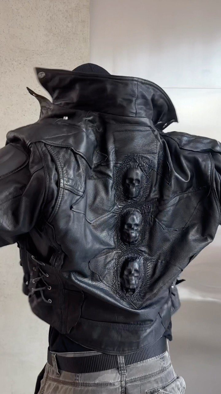Black leather jacket featuring three large embossed skulls vertically aligned on the back.