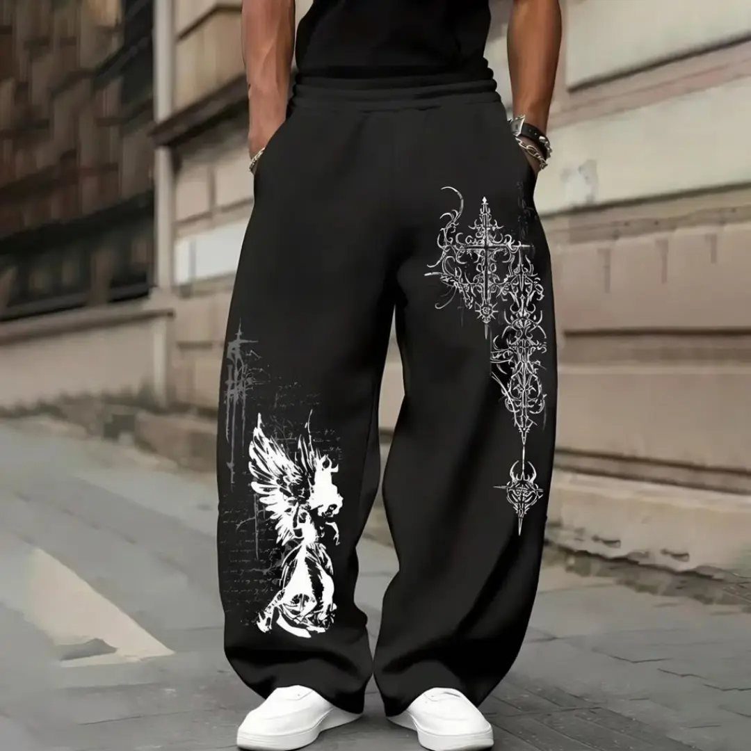 Person wearing black baggy sweatpants featuring large white graphic designs and white sneakers.