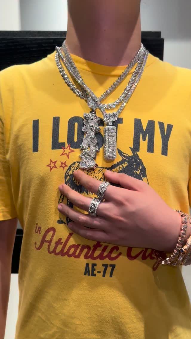 Silver diamond-encrusted necklaces, rings, and bracelets worn over a yellow graphic t-shirt.