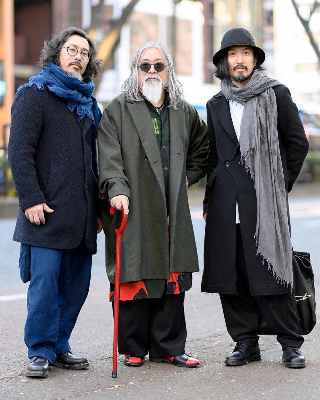 Three men posing in layered Japanese street fashion on a city sidewalk.