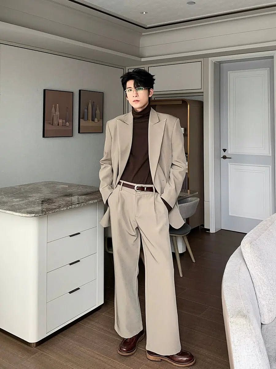 Man wearing a beige blazer, wide-leg trousers, and a dark brown turtleneck sweater.
