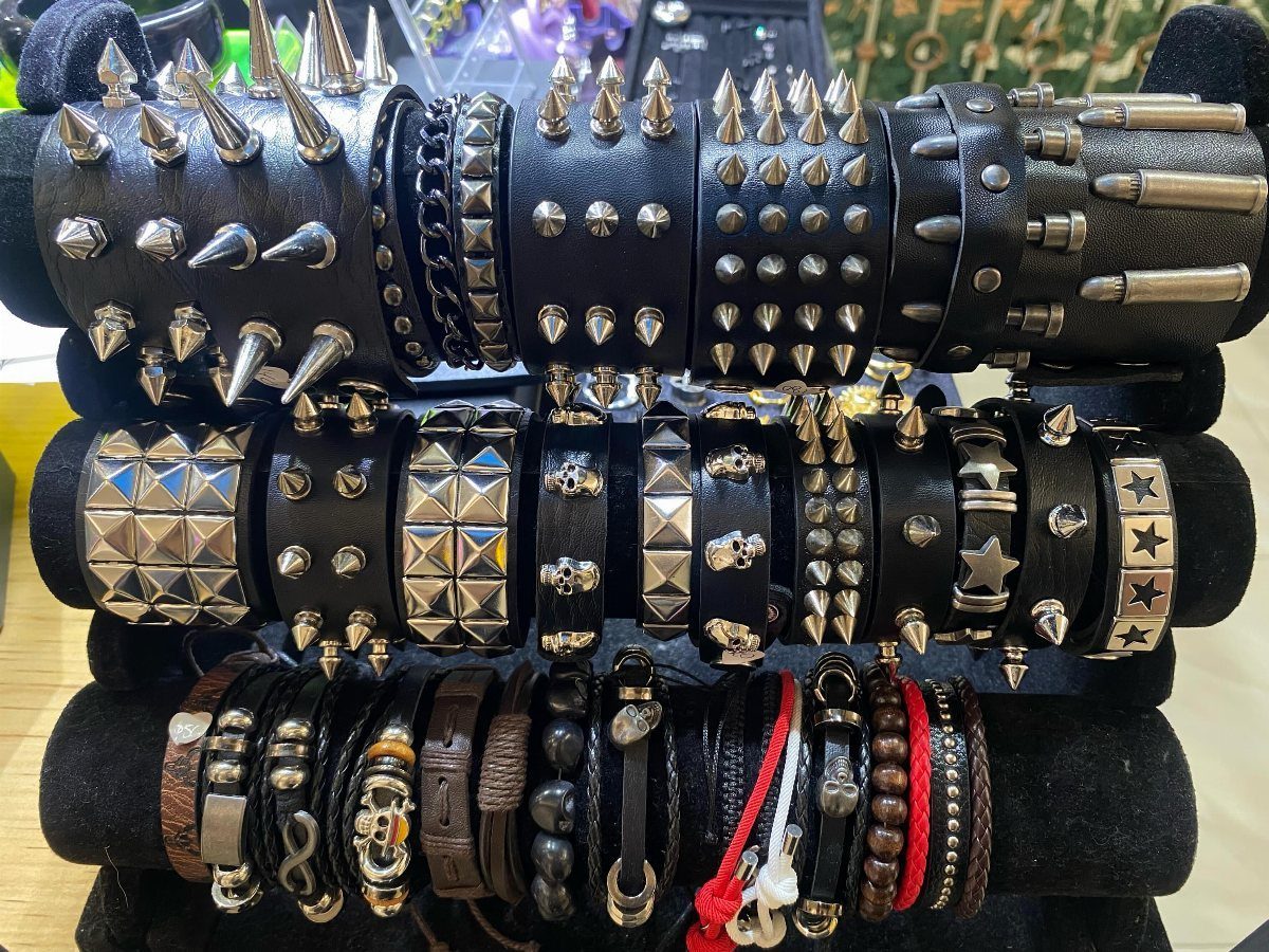 Various black leather bracelets with silver metal spikes, studs, and skull decorations on display rolls.