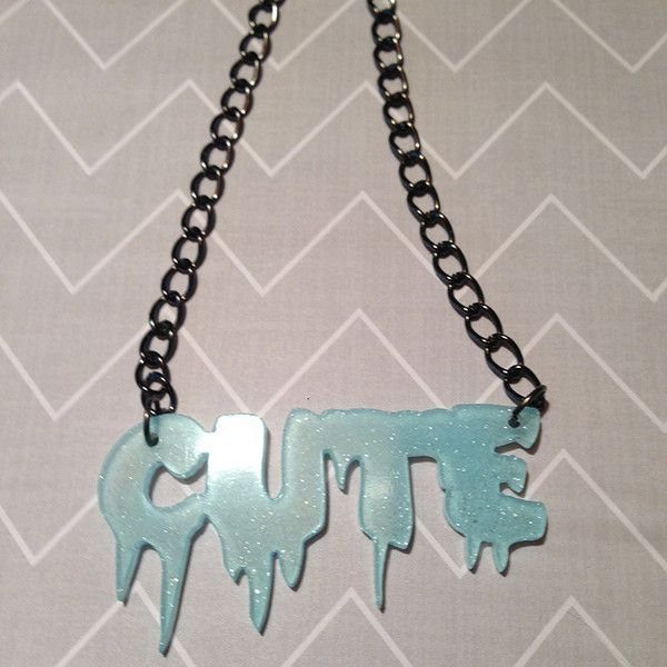 A light blue glittery pendant spelling CUTE with a dripping effect on a black chain.