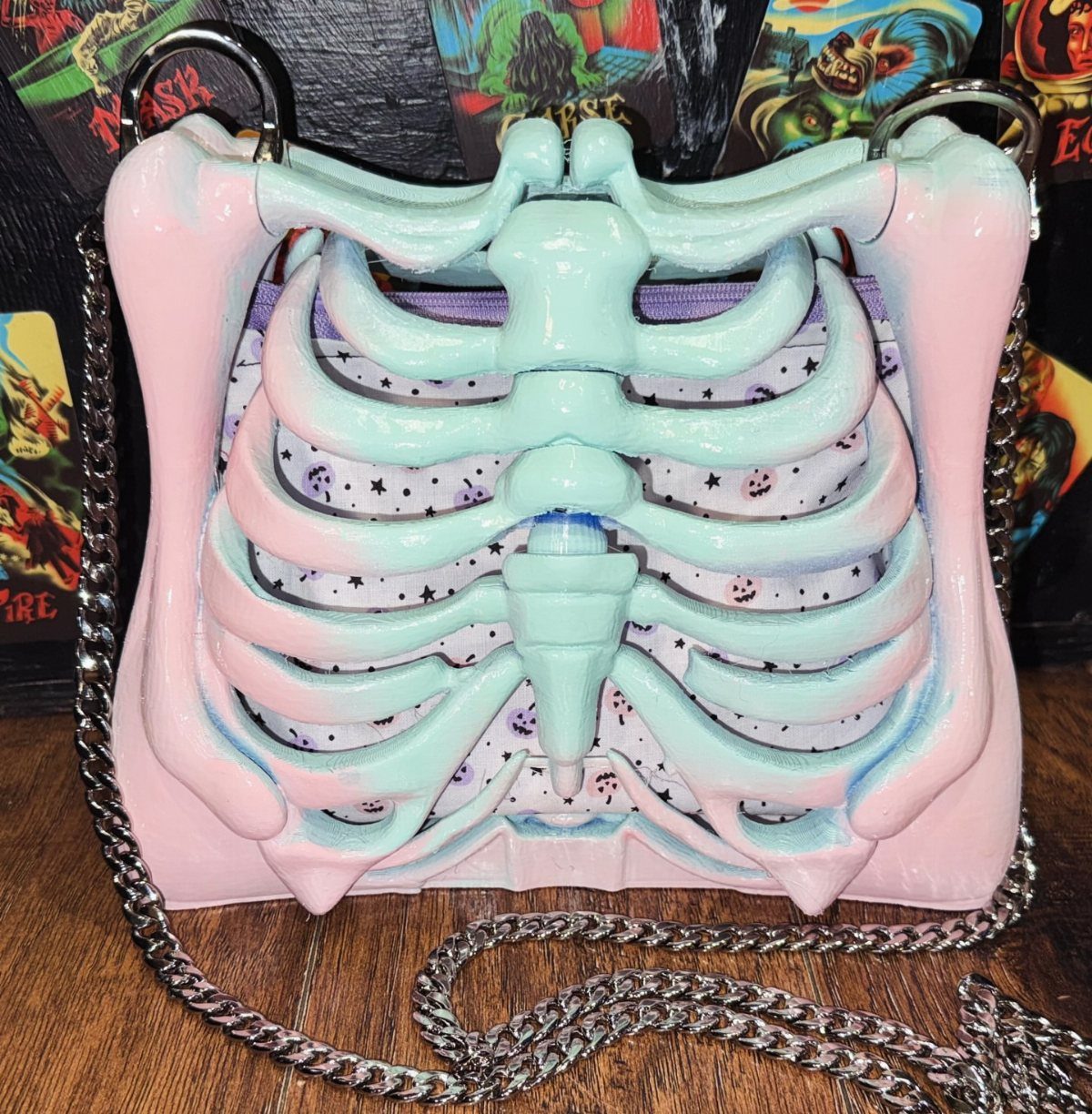 A pastel pink and mint green handbag designed in the shape of a ribcage with a silver chain.