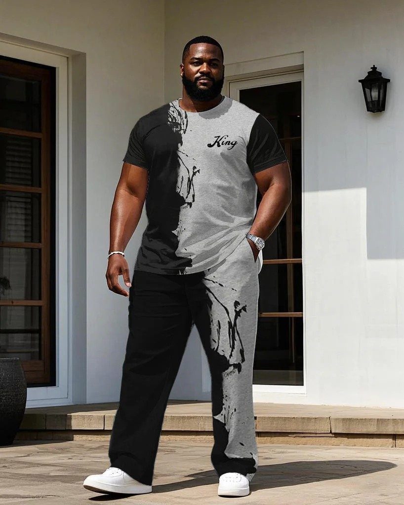 A man wearing a black and grey graphic t-shirt and matching trousers standing outdoors.