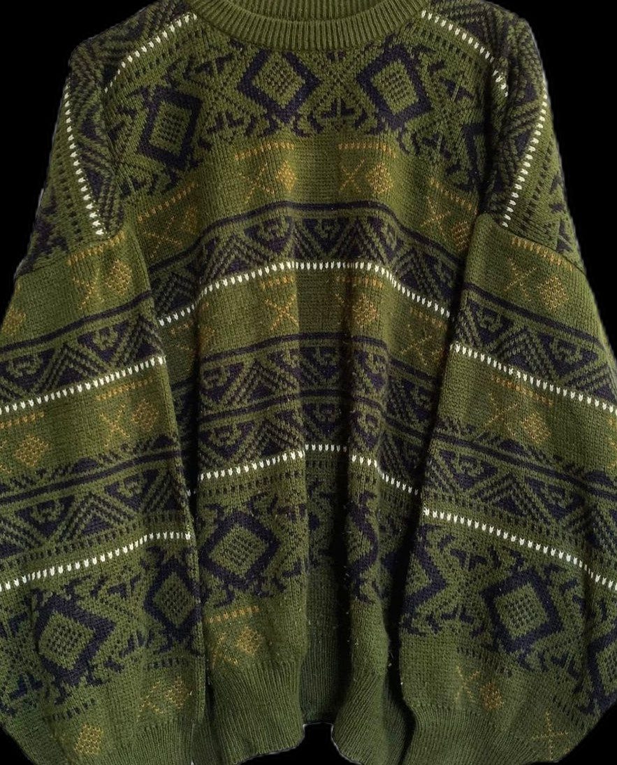 An olive green oversized knit sweater with dark blue geometric patterns and voluminous sleeves.