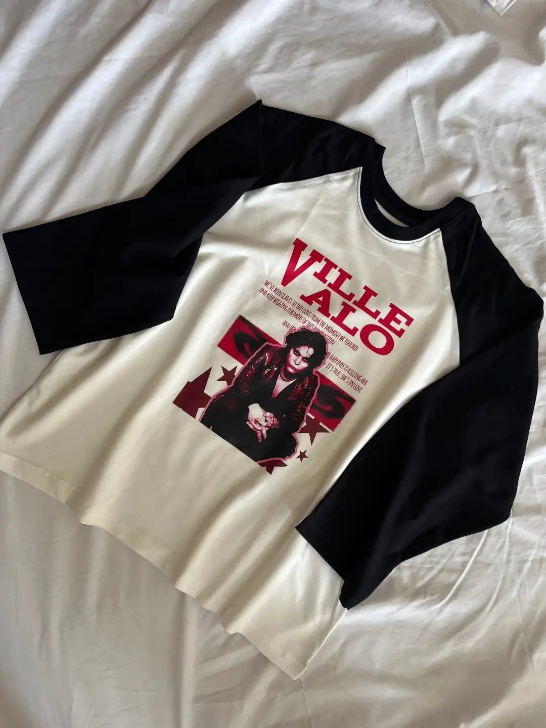 A white and black long-sleeved shirt with a red graphic print lying on white fabric.