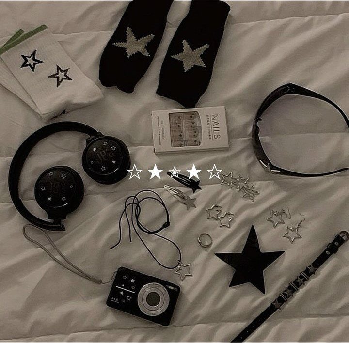 Black and white accessories including star socks, headphones, and jewelry scattered on white bedding.