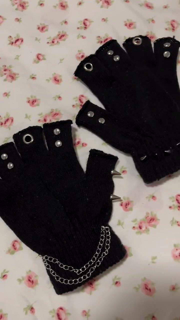Black fingerless gloves with silver studs, spikes, and a chain on a floral patterned background.