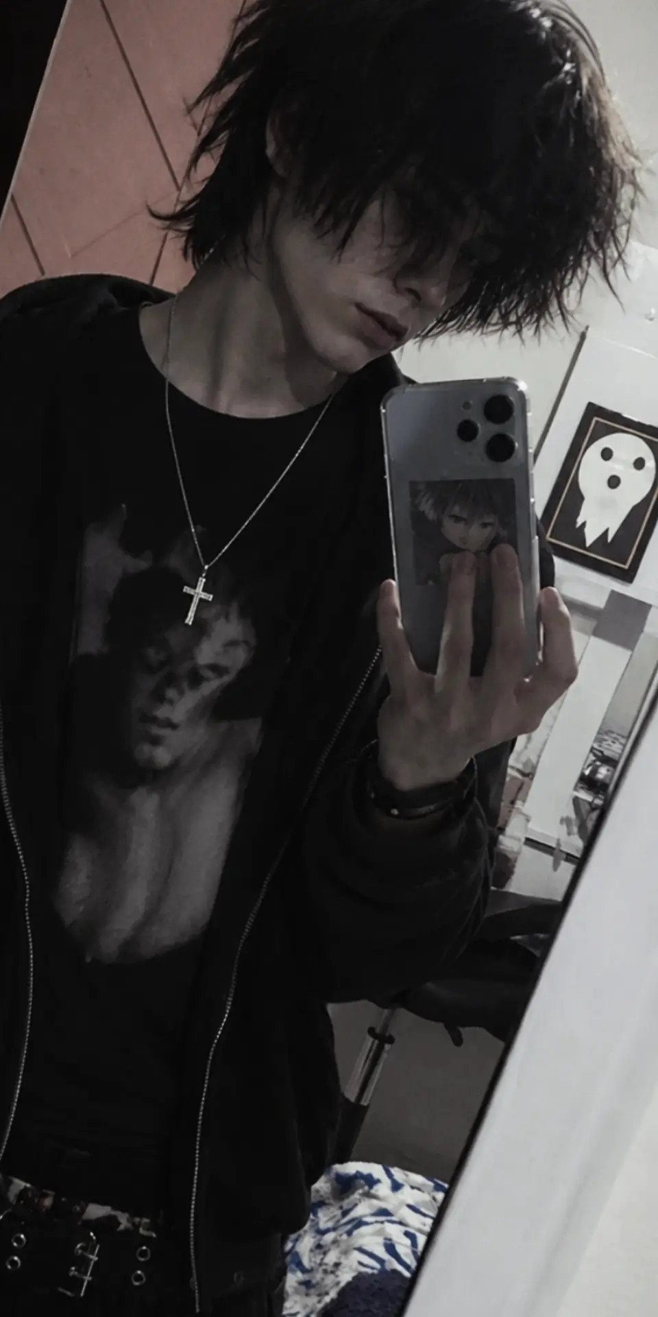A person with shaggy black emo-goth hair taking a mirror selfie in dark clothing.