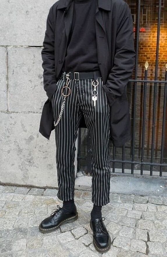 A person wearing black pinstriped gothic pants with silver chains and black leather boots.