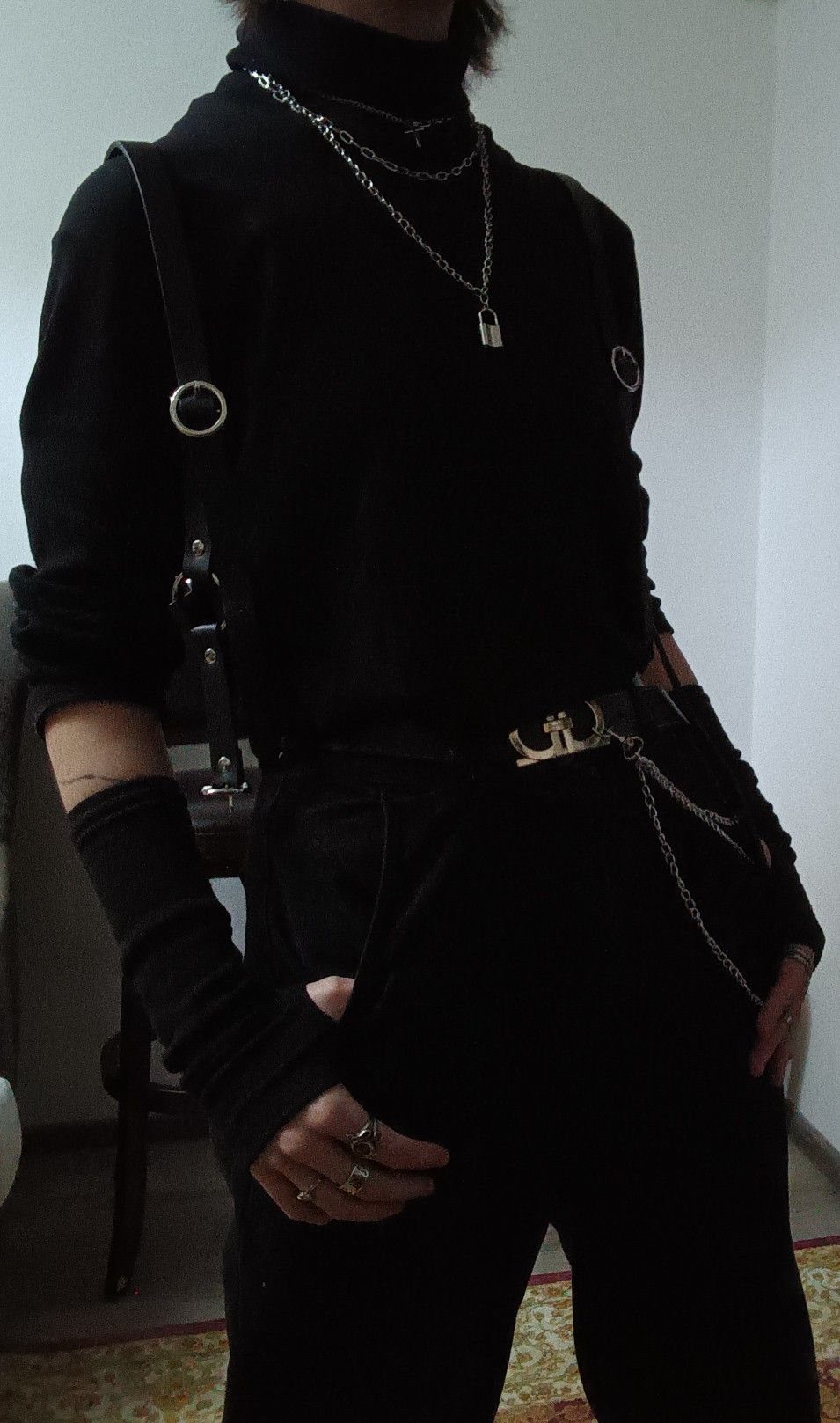 Person wearing black clothing accessorized with multiple silver chains around the neck and belt.
