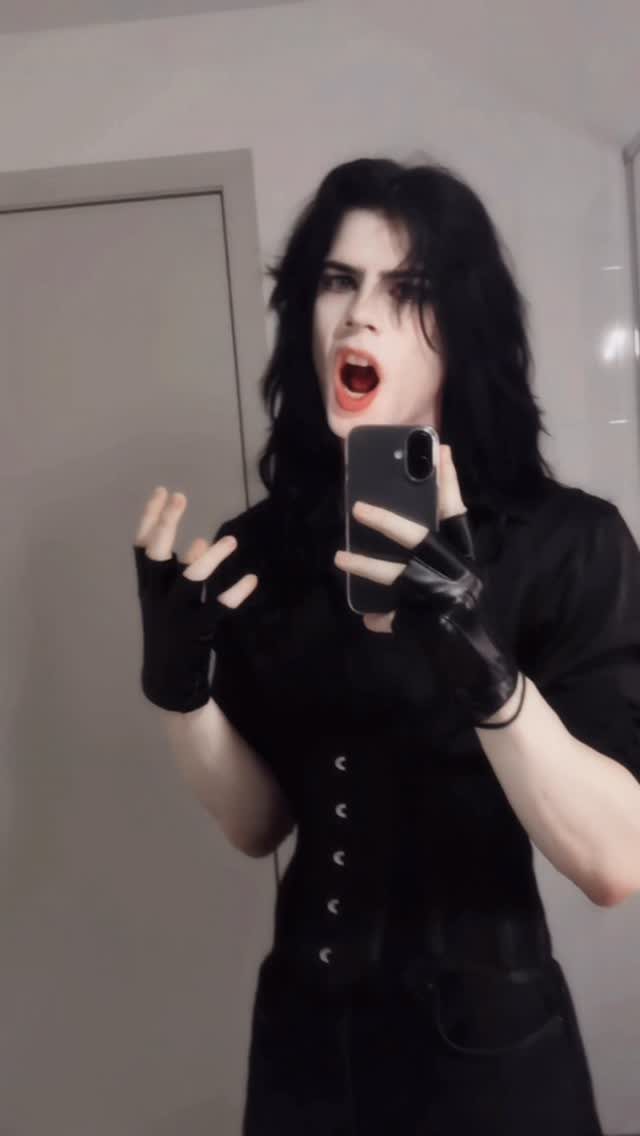 Pale person with long black hair posing in black clothing and gloves for a mirror selfie.
