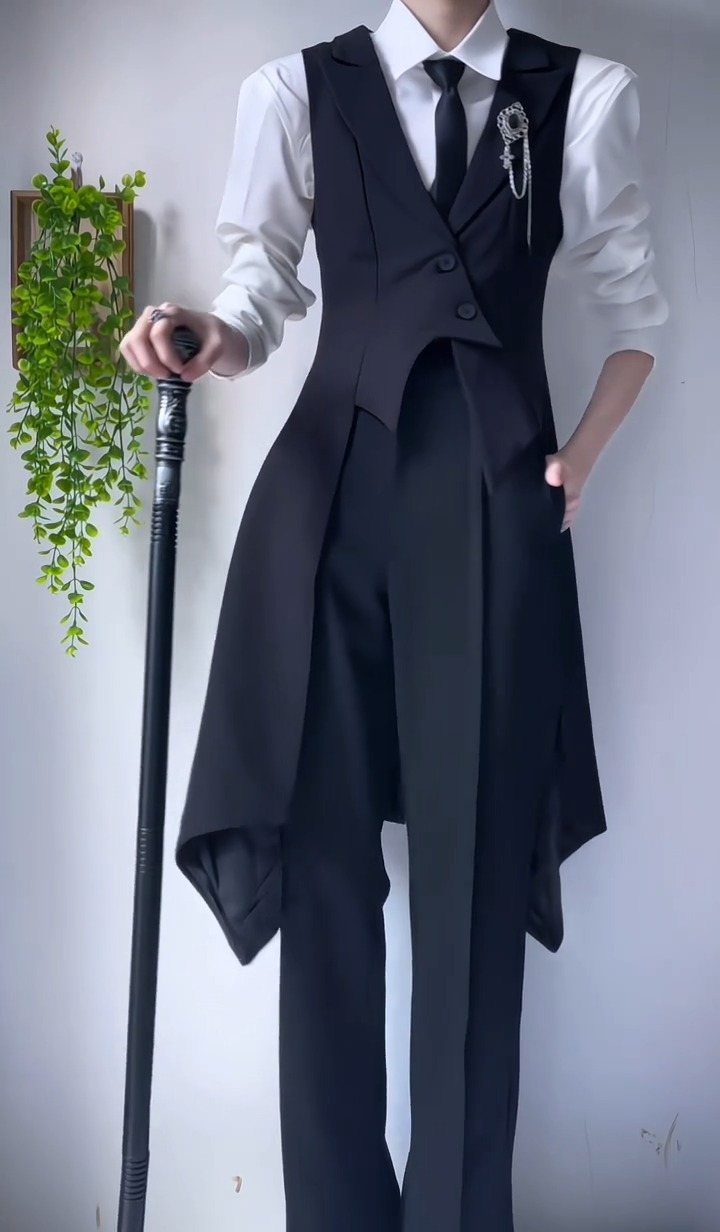 Person in a black Victorian-style waistcoat and white shirt holding a black walking cane.