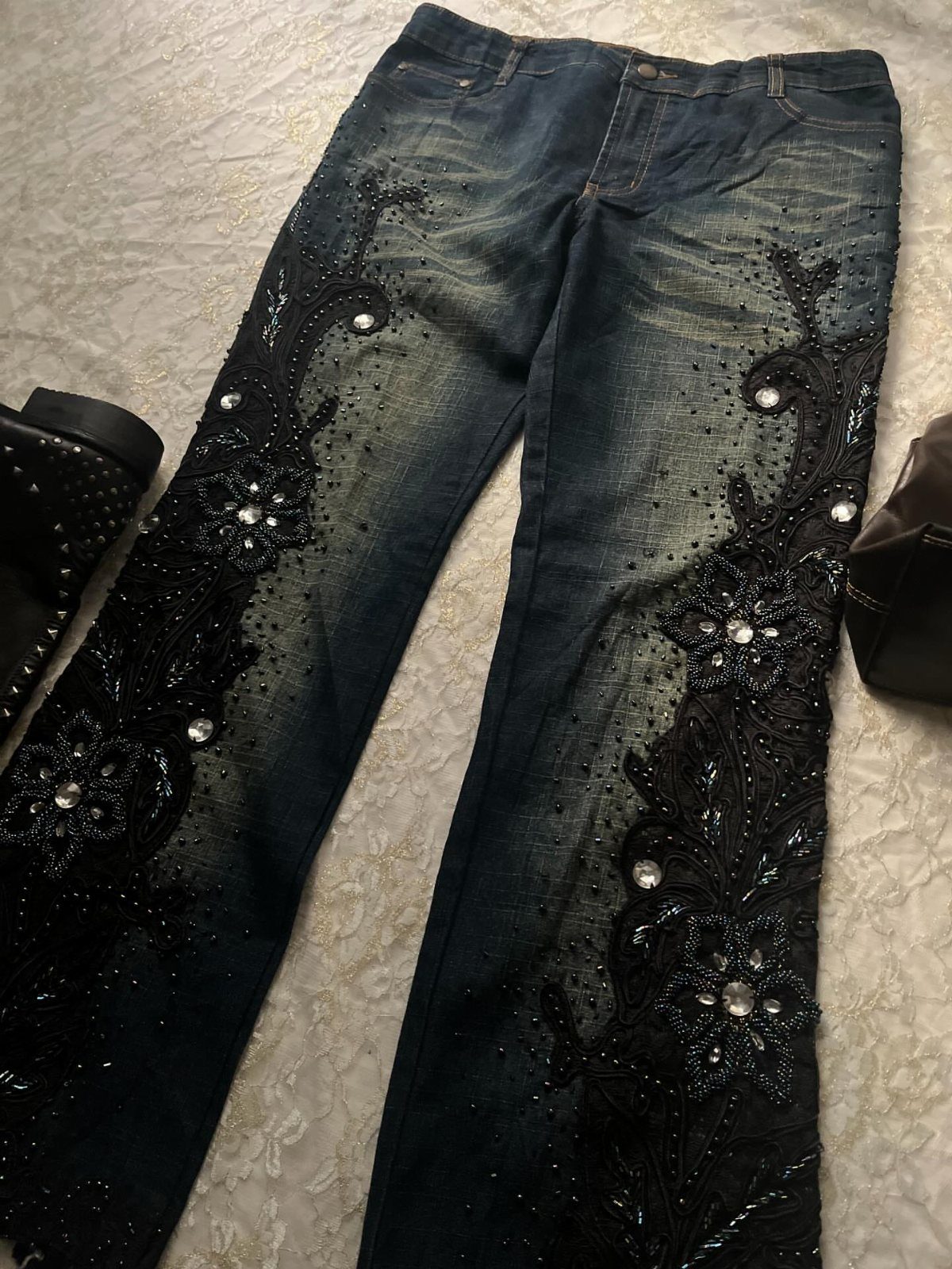 Dark blue denim jeans with black floral embroidery and sparkling rhinestone embellishments on the legs.
