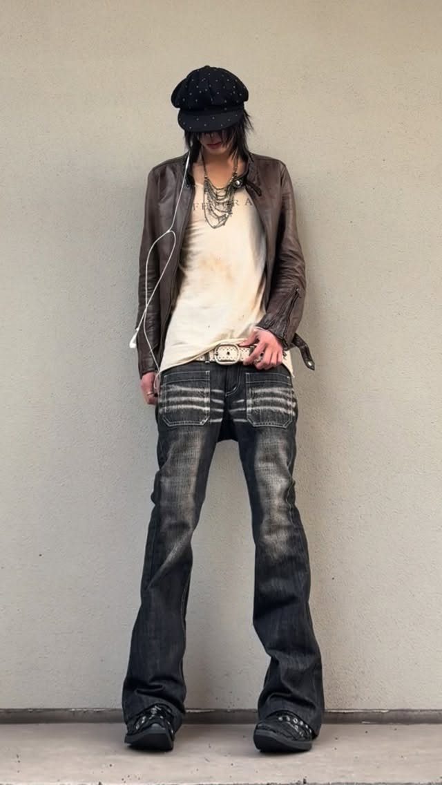 Person wearing a brown faux leather jacket, cream tank top, and dark flared denim jeans.
