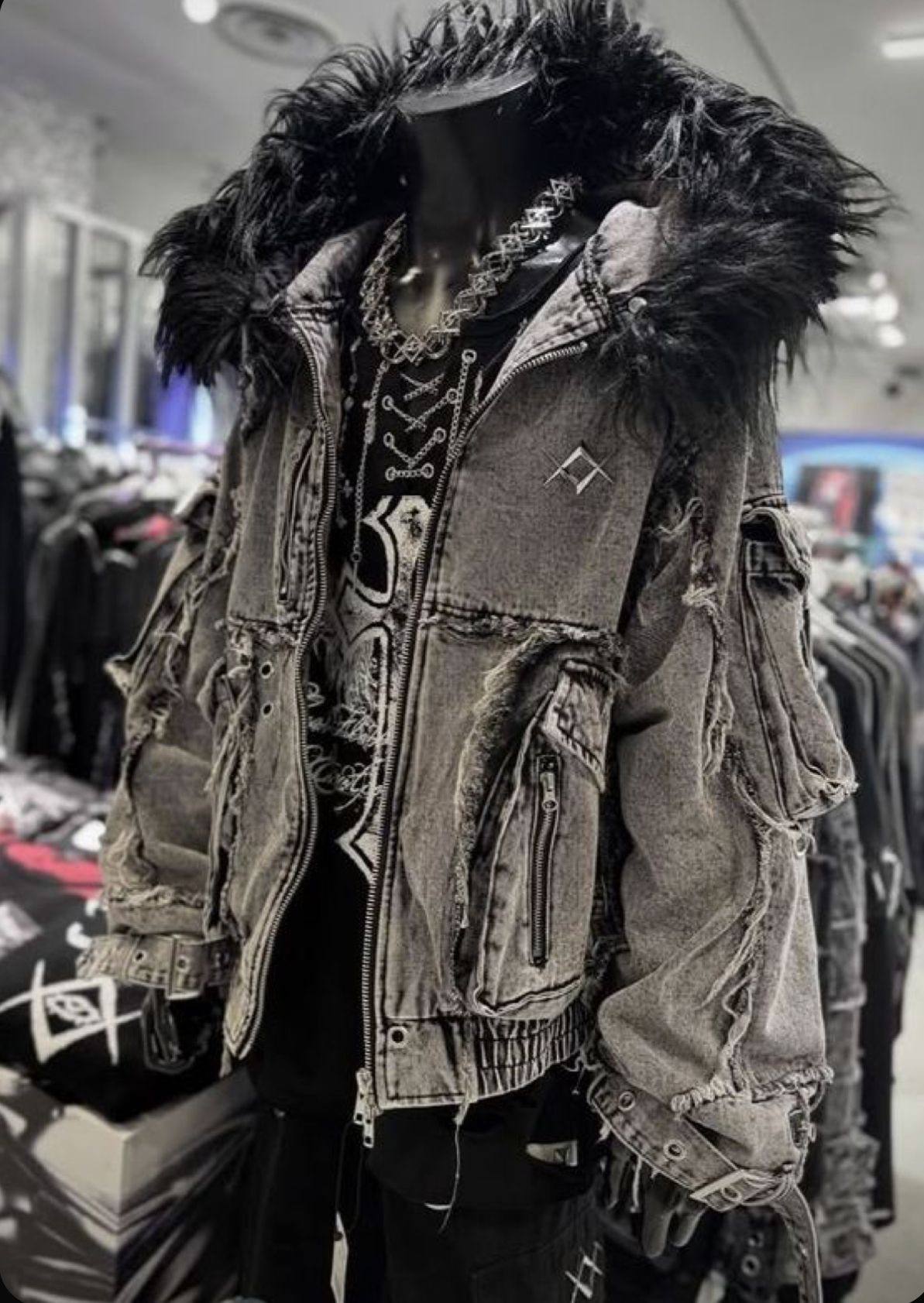 A distressed grey denim jacket with a black fur collar displayed on a mannequin.