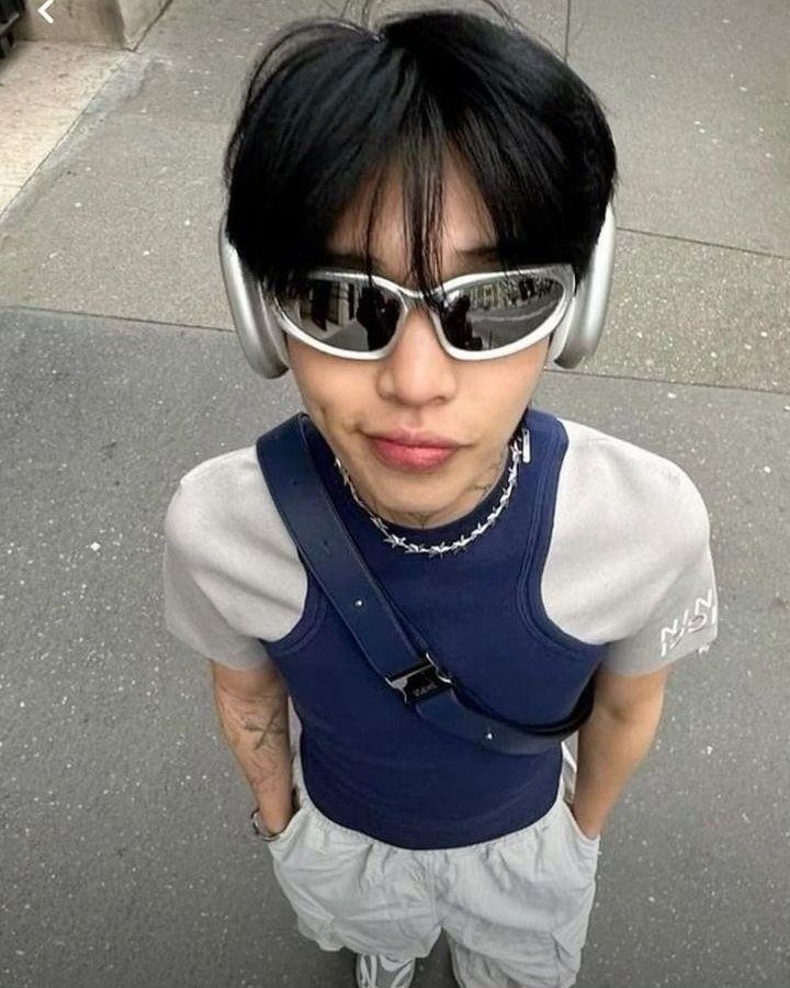 A person wearing silver futuristic sunglasses and headphones looking up at the camera.